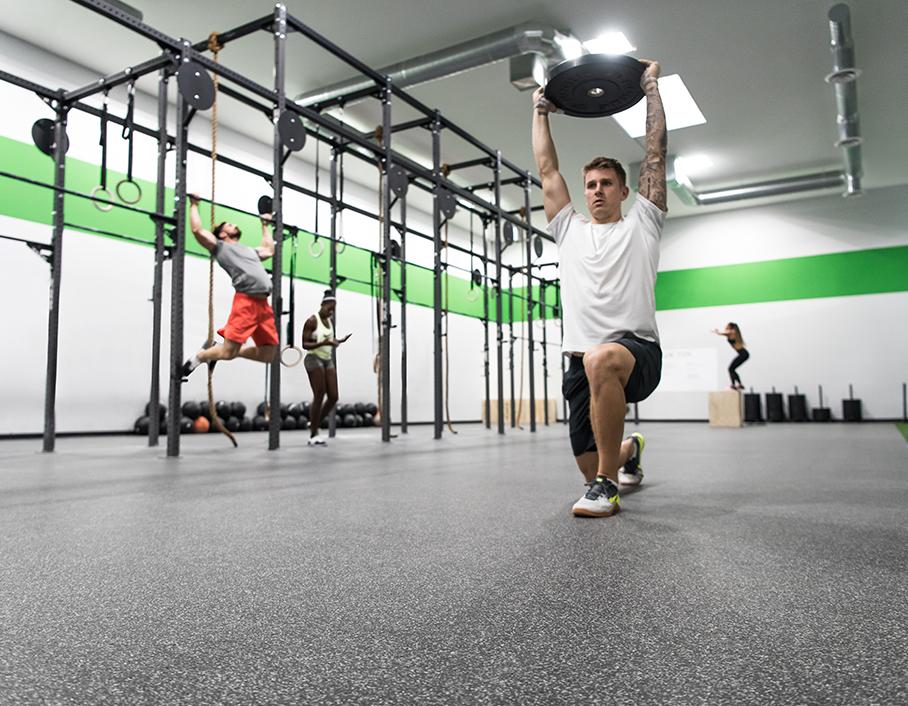 Group of people performing strength exercises in a modern gym setting.