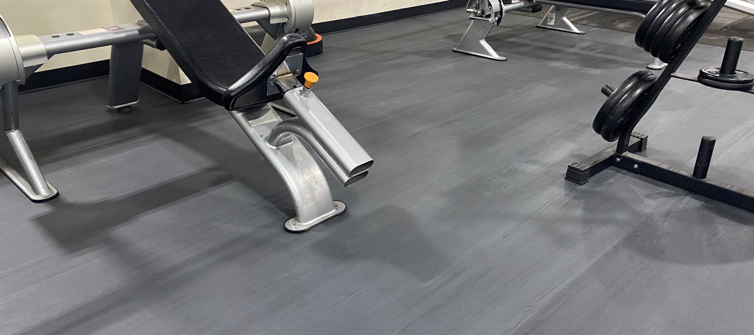 A shot of a gym where you see an incline bench press on a Moxie flooring